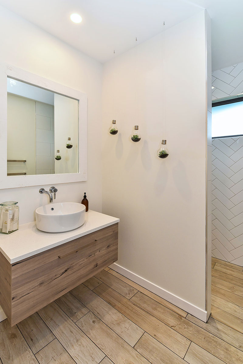 Guest Bathroom with wooden floor tiles, wooden vanity and herringbone style feature wall in shower