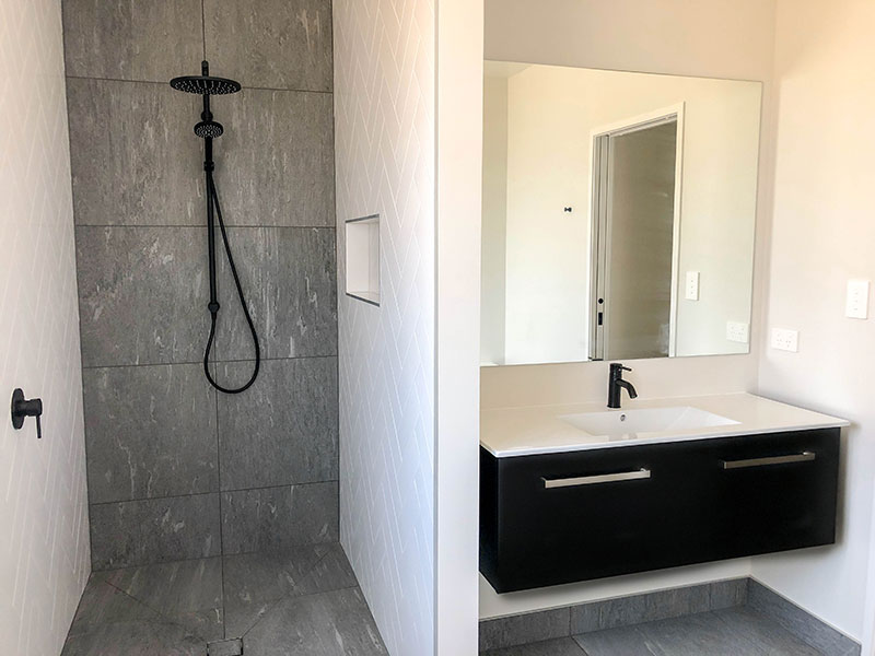 Black Elementi tapware and shower with grey tiled wall and floor, white subway herringbone and black vanity