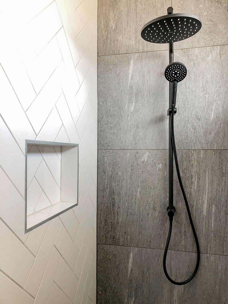 Black Elementi Shower Slide and dumper in shower with grey tiled wall and floor and white subway herringbone