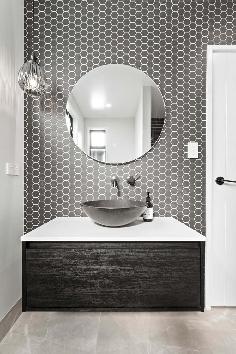 Stunning white and black bathroom with black timber vanity, black mosaics and black basin in designer home