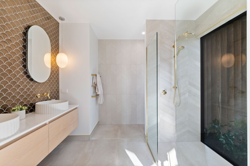 Luxurious Ensuite Bathroom with copper fishscale tiles, window in shower, brass fittings, robertson concrete basins