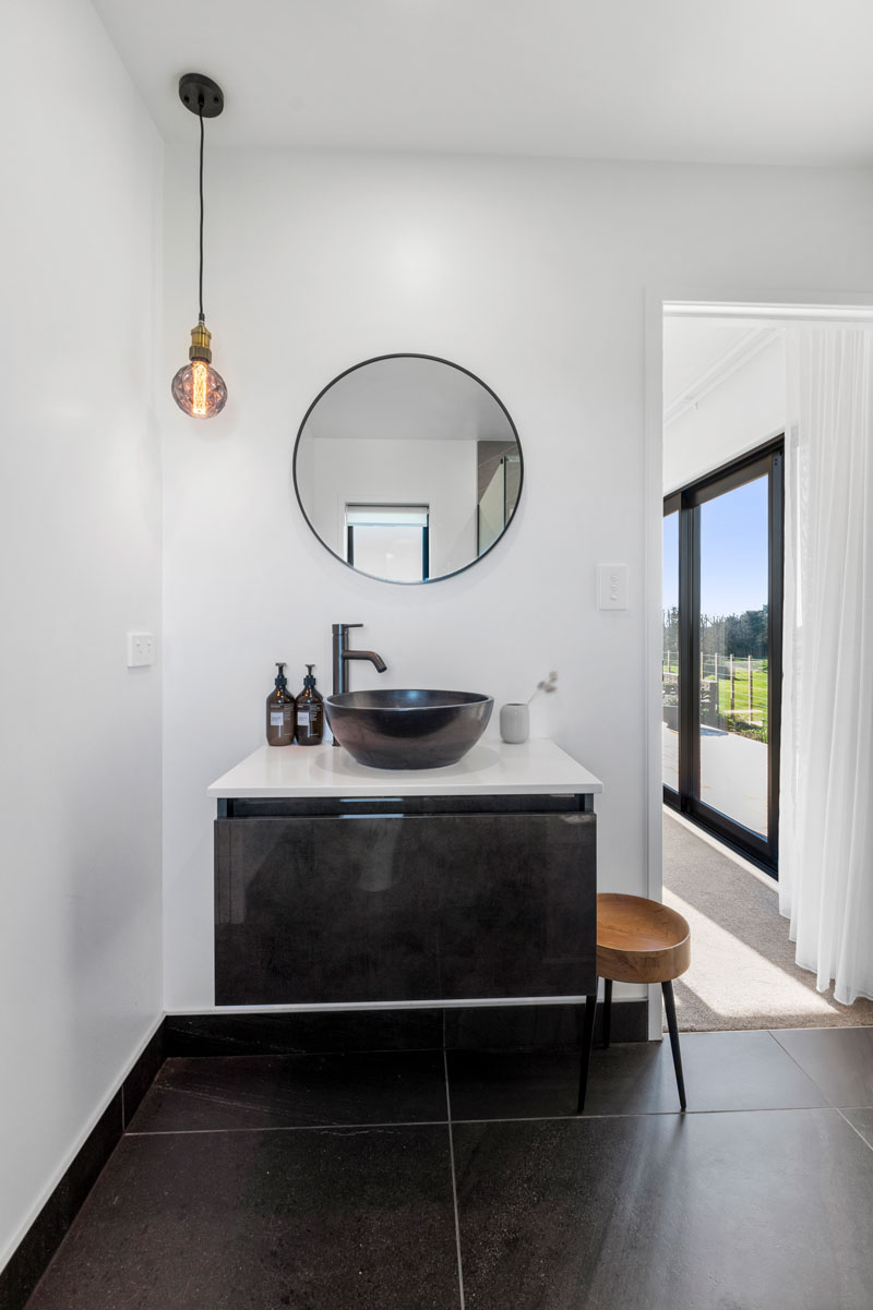 Gorgeous light bathroom with dark charcoal vanity, basin and tiles in award winning Pukekohe home