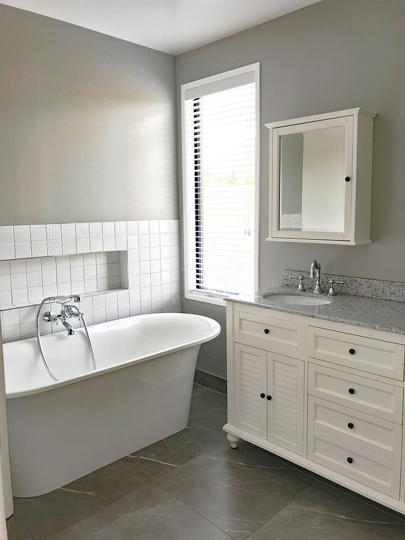 Gorgeous White and grey bathroom with grey marble tiles and white patchwork tiles. Colonial traditional style vanity, taps and cabinet