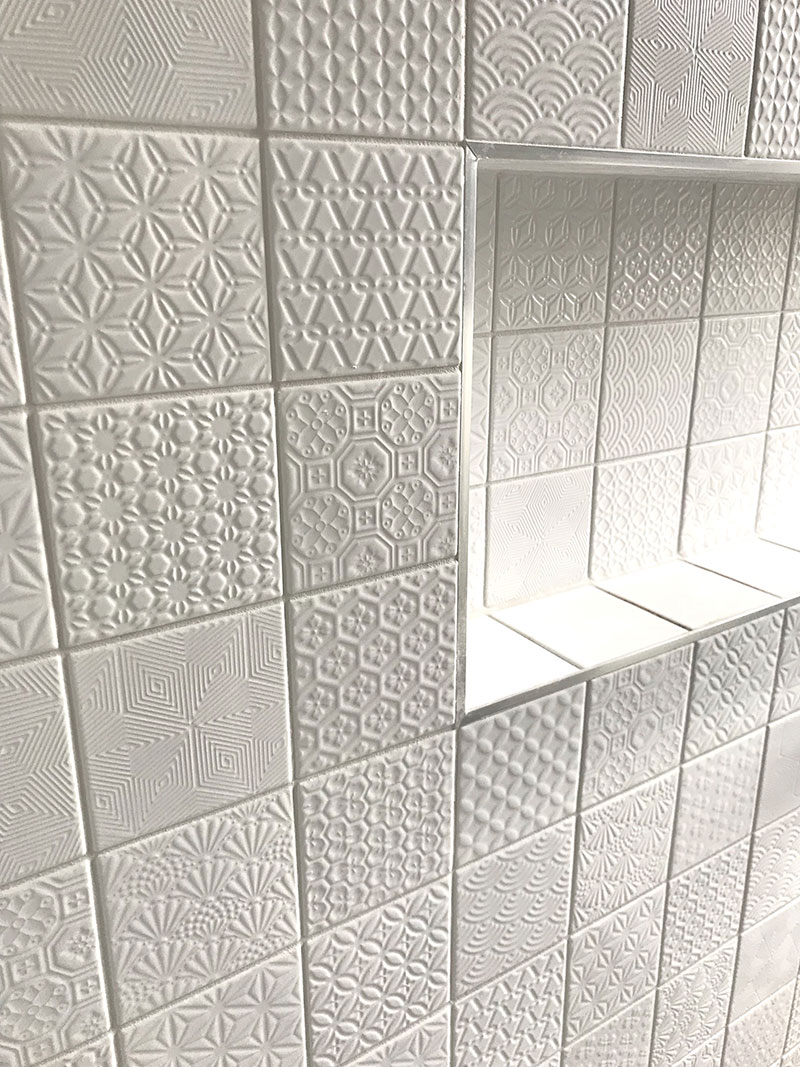 Close up of beautiful white, textured, patchwork style, mosaic tiles and recessed shelf