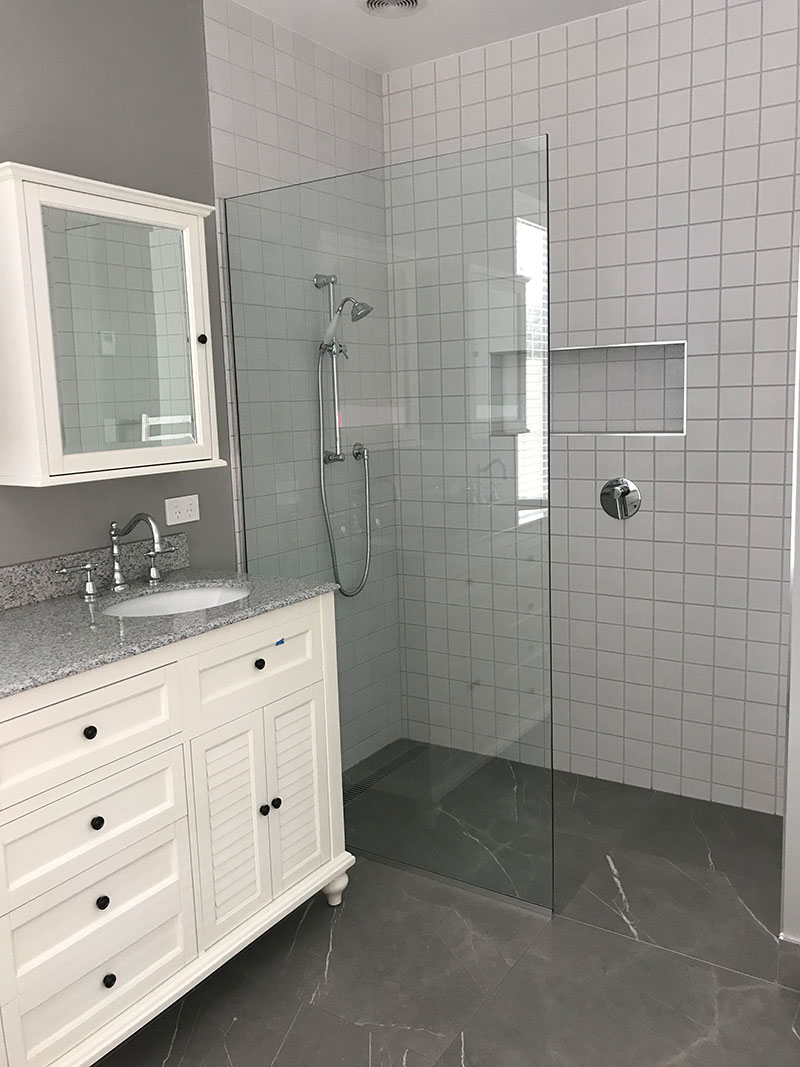 Traditional style vanity, tapware and cabinet with grey marble floor tiles. Large walk in shower with white patchwork wall tiles