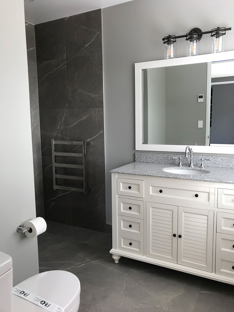 Colonial style vanity in ensuite bathroom with grey marble tiles on floor and shower walls.