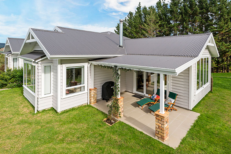 Colonial Style award winning home, clad in weatherboard with brick pillars surrounded by native bush