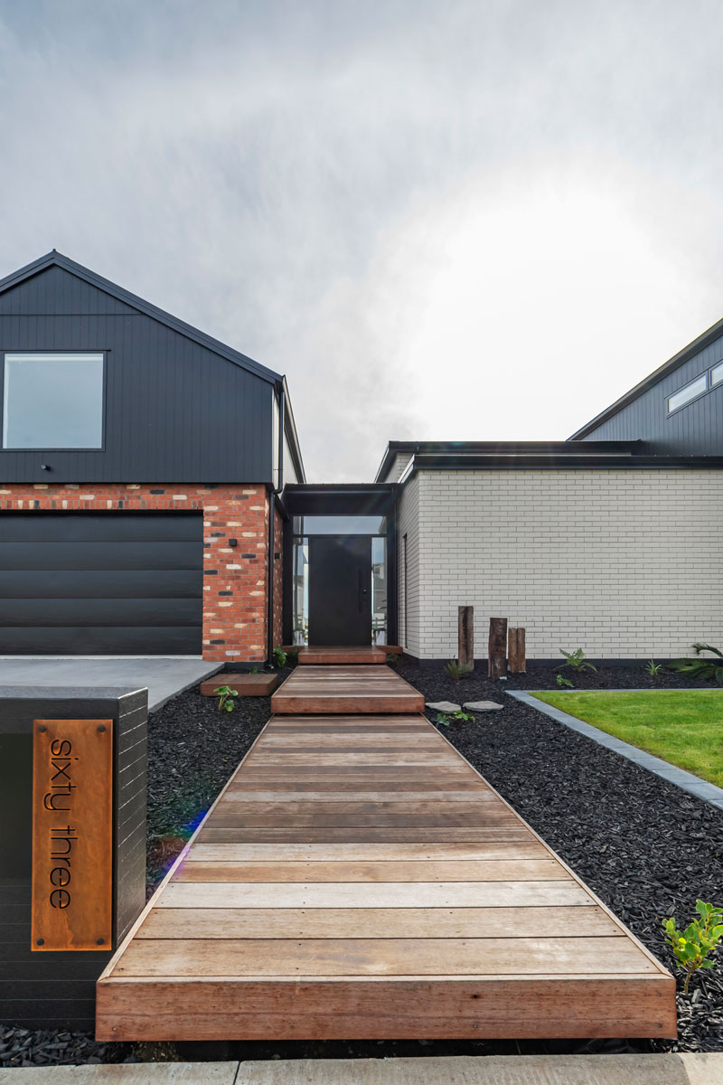 Front of designer home with Black Axon panel, white brick and Red recycled brick features, timber boardwalk