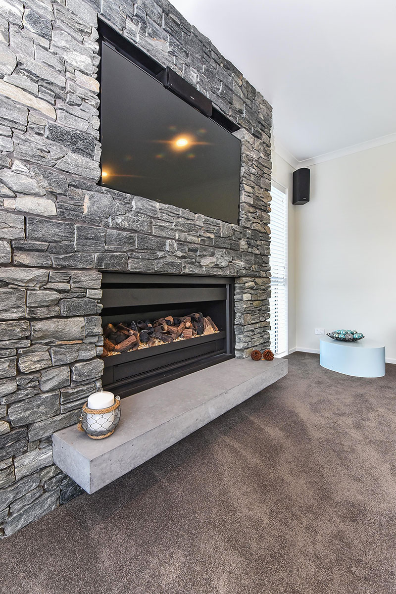 Beautful schist fireplace with recessed TV above and concrete hearth in award winning home