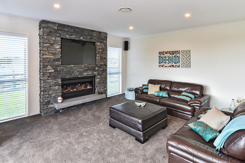Large schist fireplace with TV in lounge with turquoise accents and concrete hearth