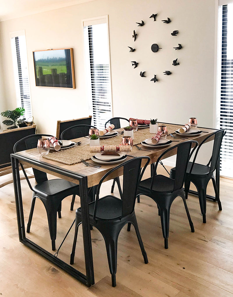 Rustic dining table with large bird wall clock in Paerata Rise showhome