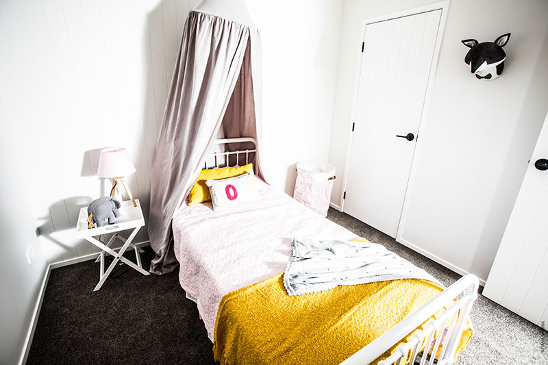 childs bedroom with canopy over bed, pink bed with yellow accents and metal bed frame