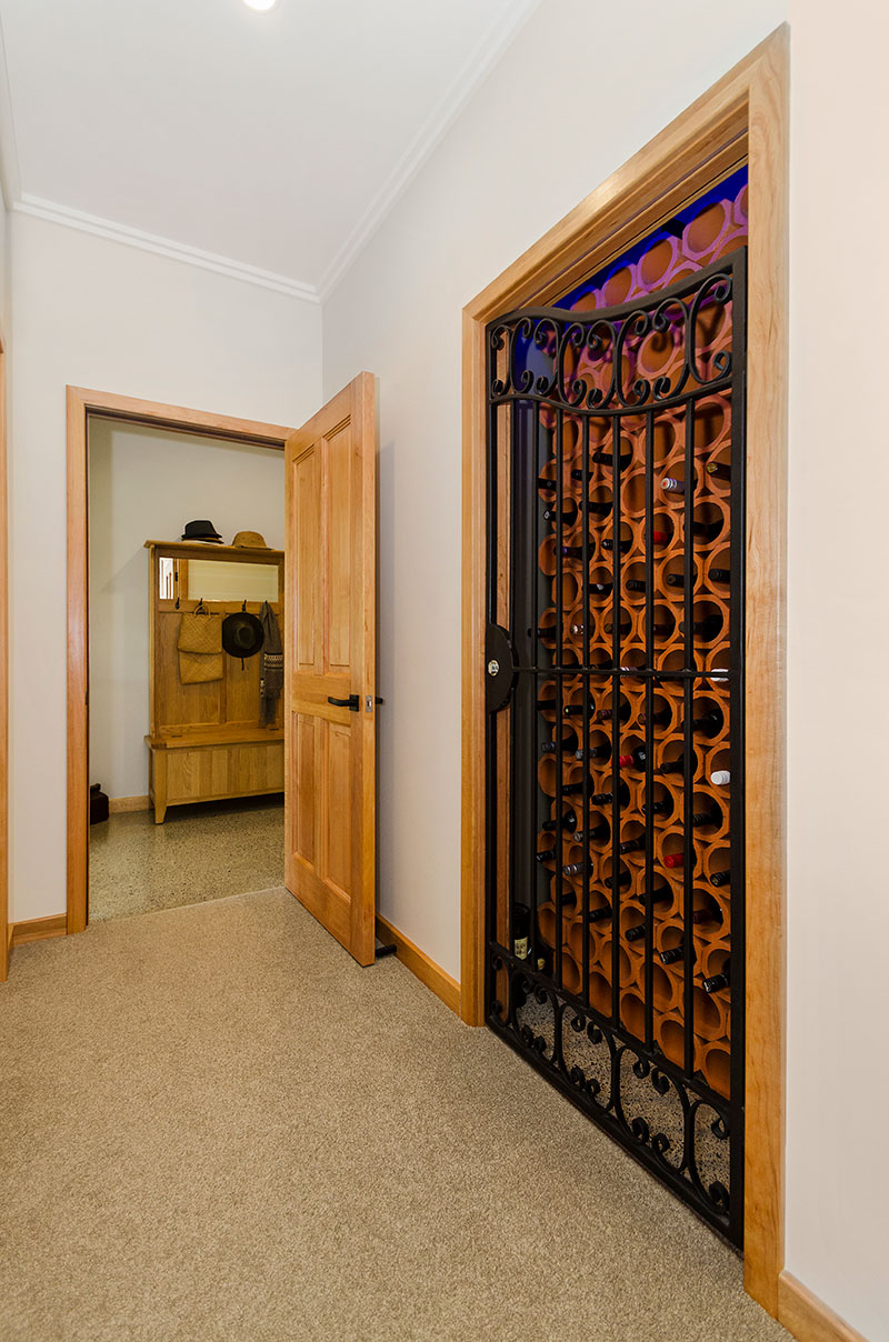 Wine cellar with wrought iron gate, terracotta pipe and wooden accents in award winning home