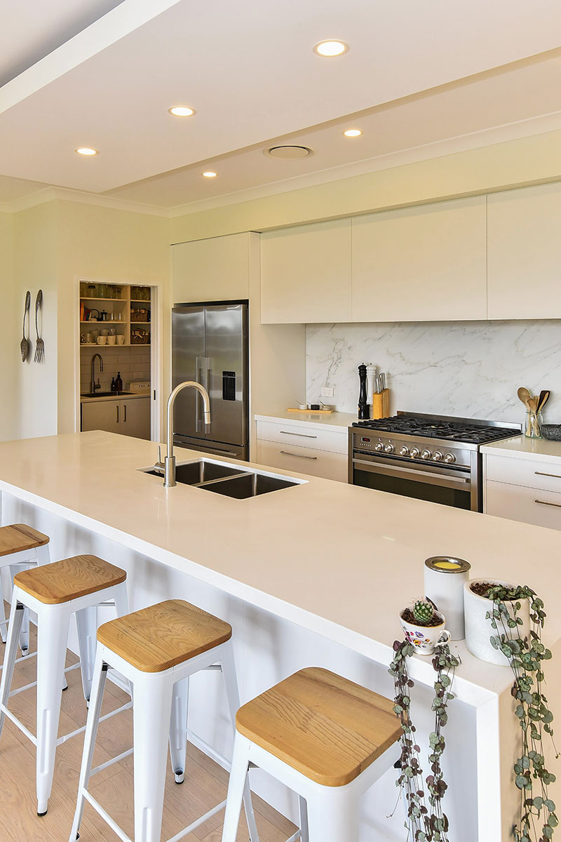 Light scandinavian style kitchen with white cabinets & benchtop, marble splashback and butlers pantry.