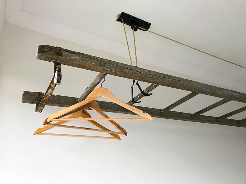 Stunning rustic timber ladder, on pulley system, suspended over bench for use as a drying rack