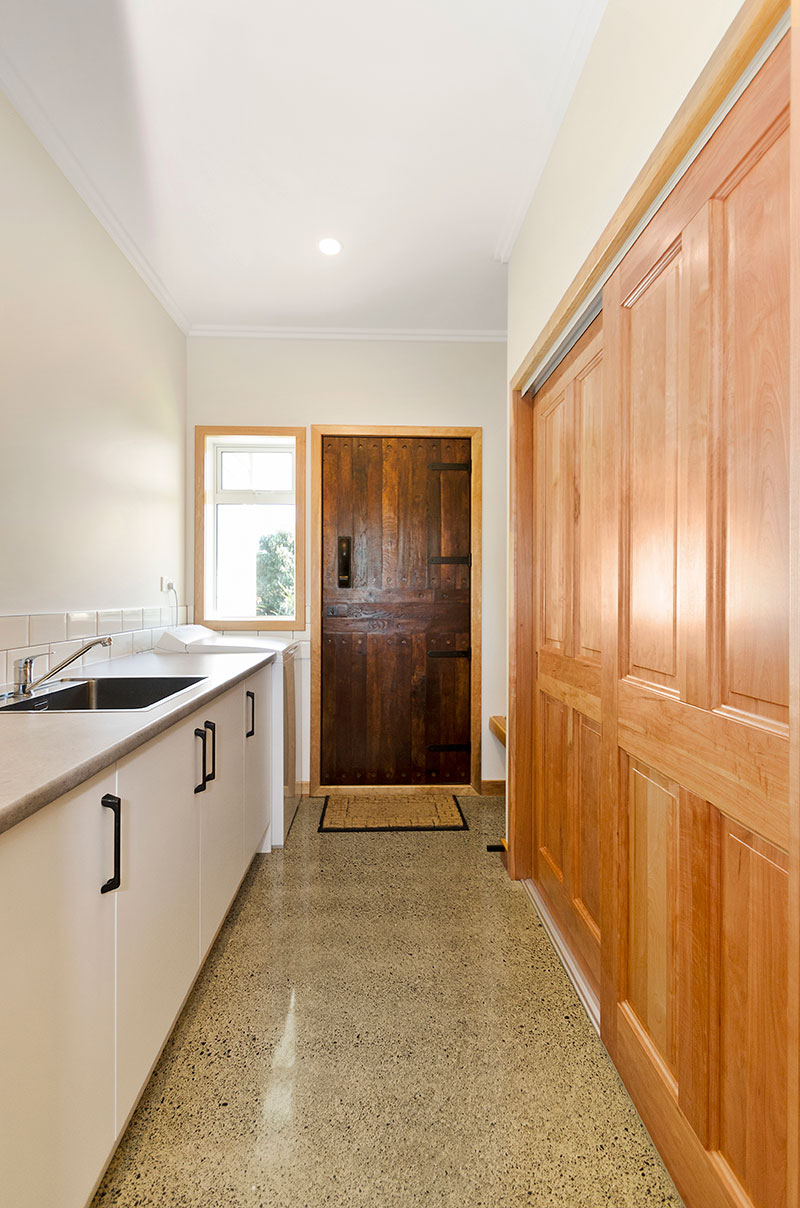 Beautiful large laundry room with stunning rustic barn style timber door, timber cupboard doors and concrete floor