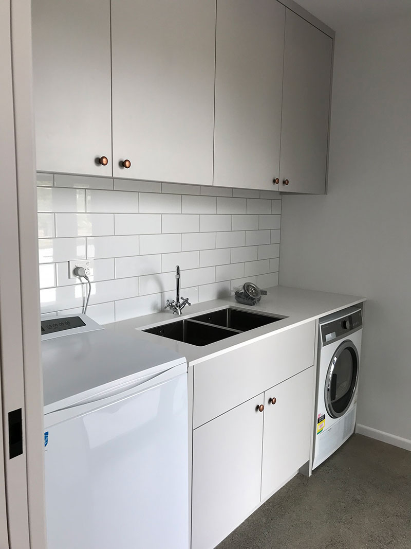 Lovely, simple, yet classic laundry room with traditional taps and handles and white subway tile splashback