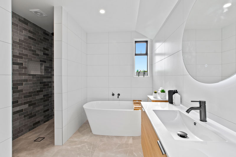 Gorgeous light bathroom with dark charcoal subway tiles in shower from Tile Space