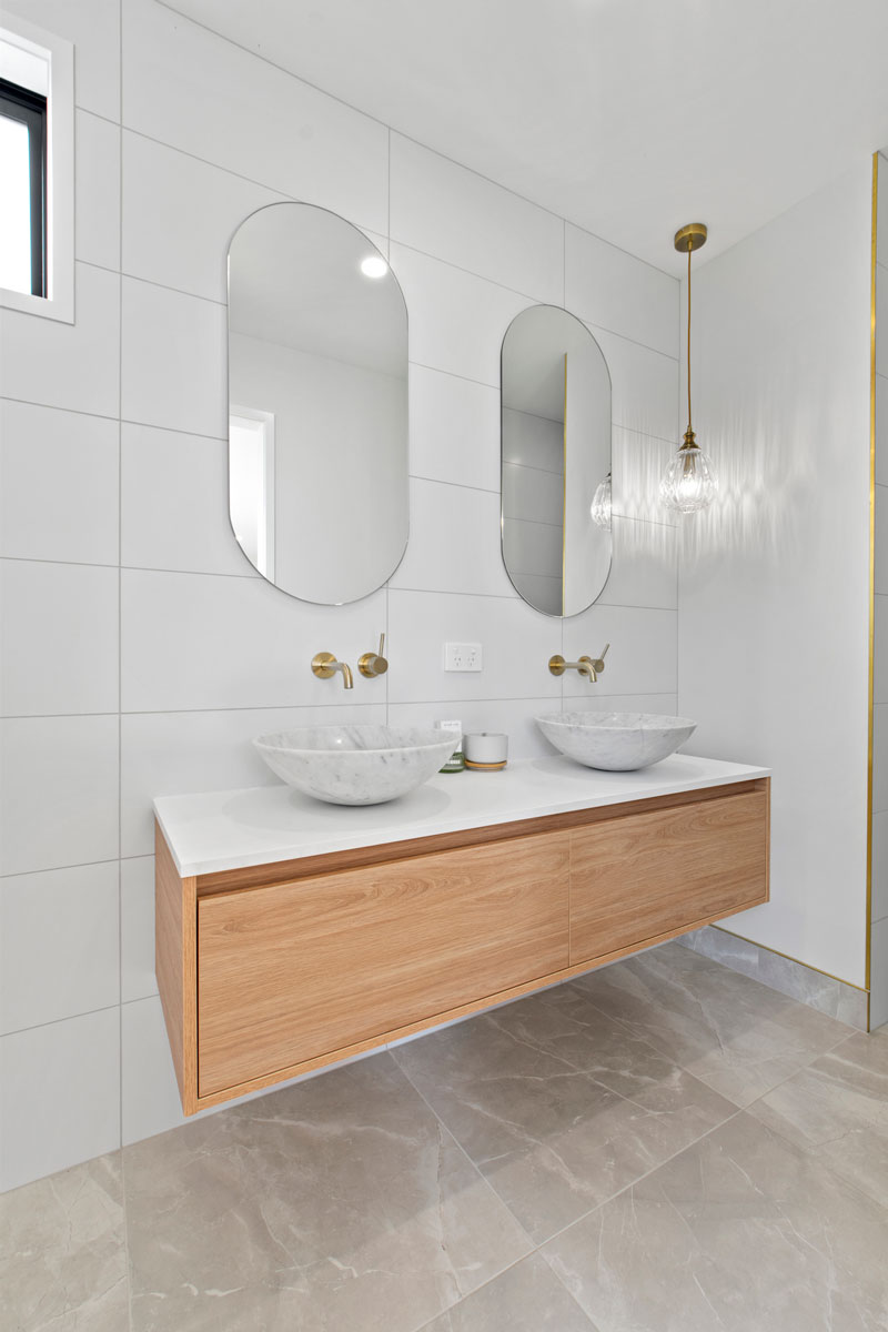 Gorgeous light bathroom with double basin, timber New Tech vanity, oval mirrors and feature light