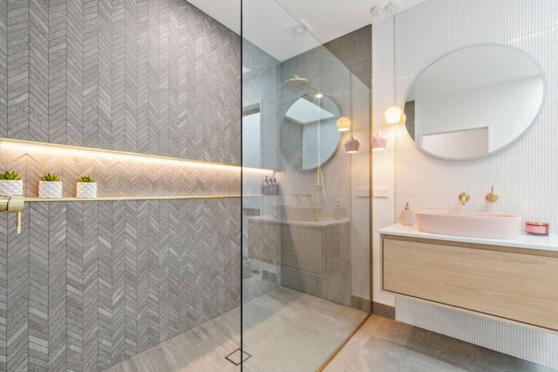 Luxurious Bathroom with grey stone chevron tiles, led shower shelf, pink robertson concrete basin, Newtech vanity