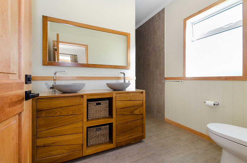 Bathroom with Gorgeous Wooden vanity with stone basins, wooden accents and mirror 