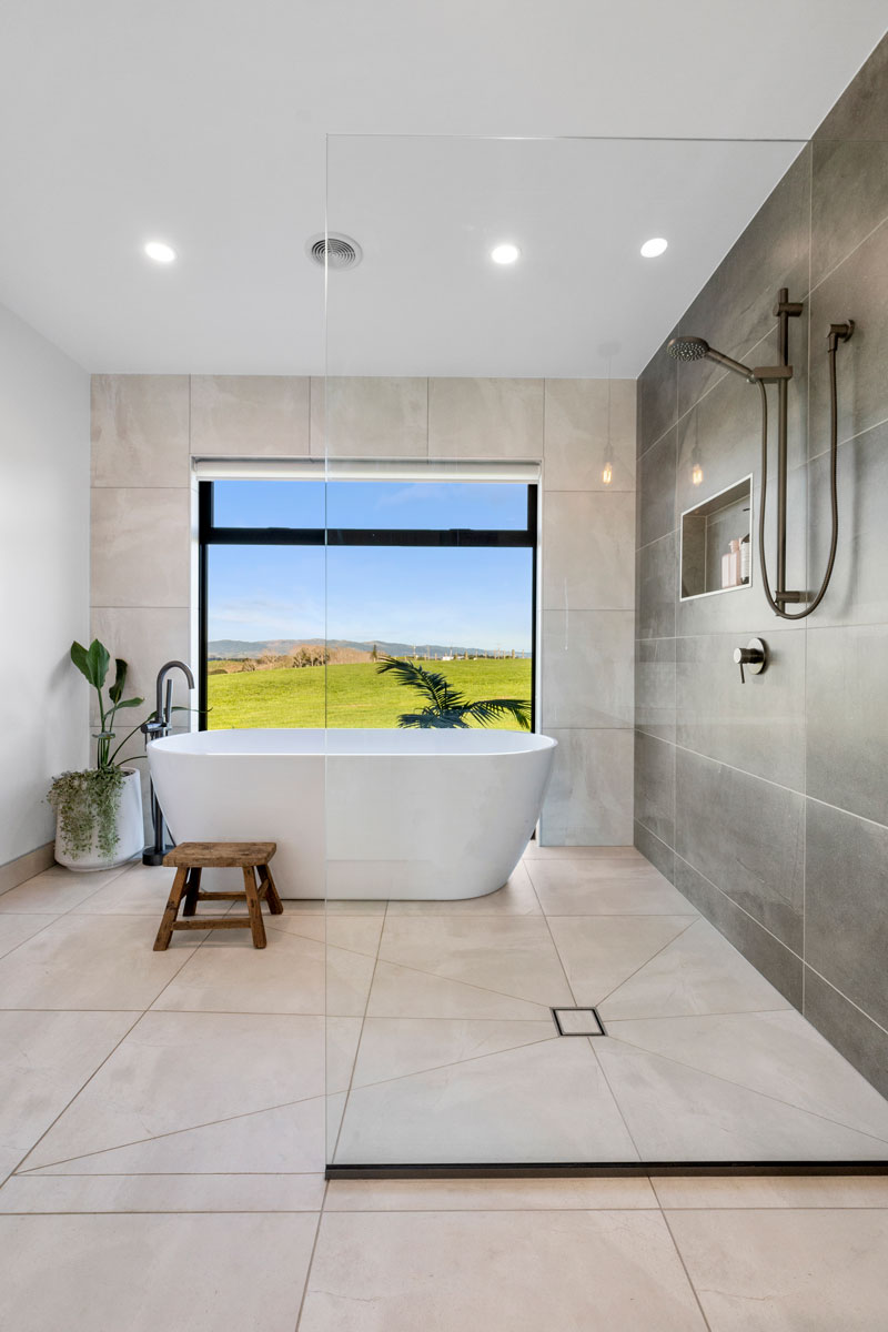 Gorgeous light bathroom with open shower and large freestanding bath with view