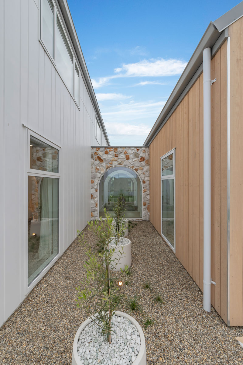 Gorgeous mediterranean inspired home with irregular stone vintage white wall, arched windows, Precision Homes showhome