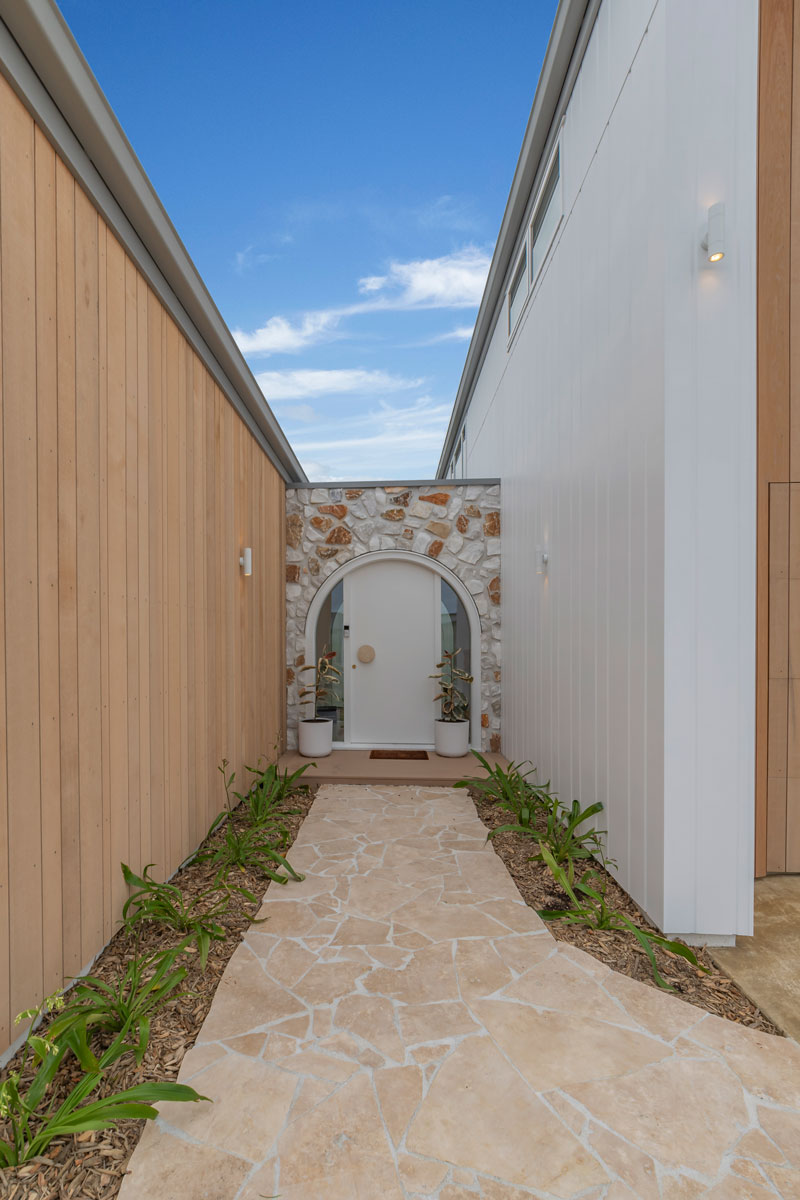 Gorgeous mediterranean inspired home with irregular stone vintage white wall, arched front door, Precision Homes showhome