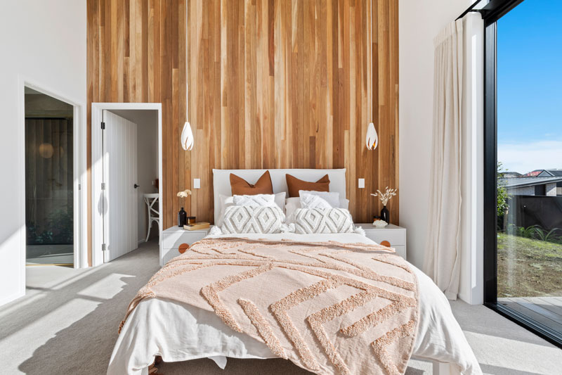Stunning master bedroom with timber feature wall and hanging lights in our new showhome in Paerata Rise