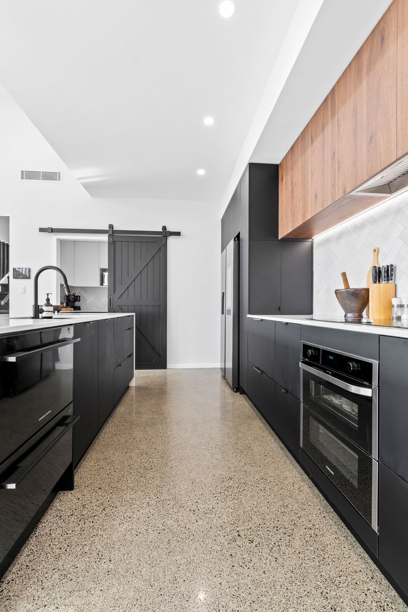 Gorgeous kitchen with black cabintry marble benchtop, and timber accents in designer home in Glenbrook