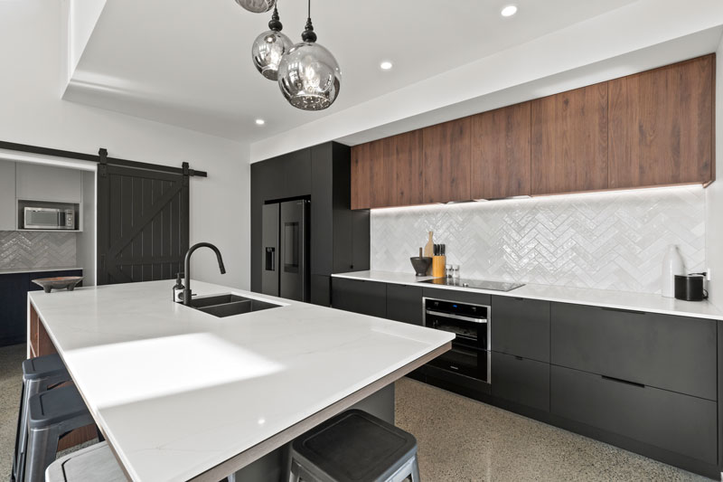 Gorgeous kitchen with black cabintry marble benchtop, and timber accents with feature lighting