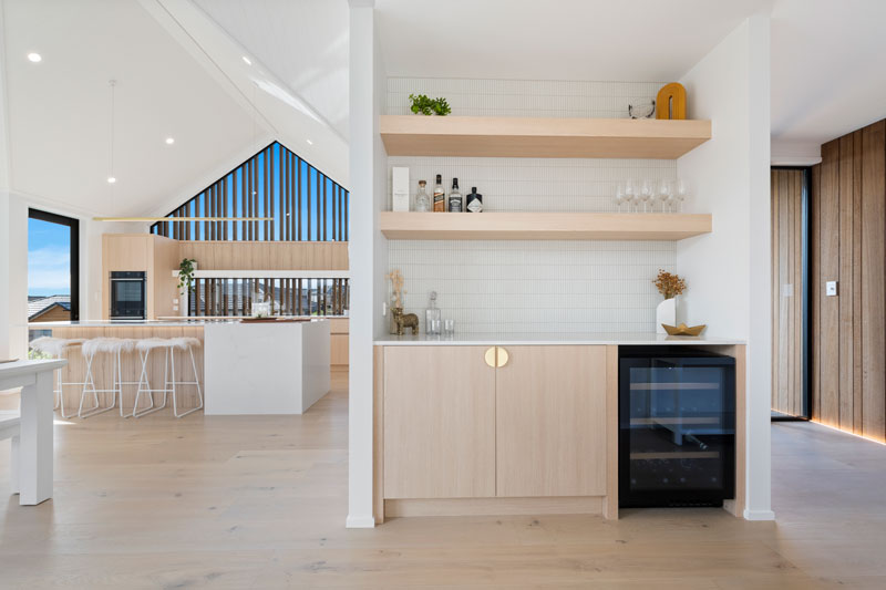 Gorgeous light timber scandinavian kitchen and bar area with brass fittings and finger tiles in Paerata Rise showhome