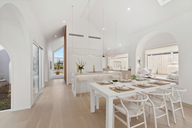 Gorgeous light mediterranean inspired kitchen with brass fittings, arched window seat, arch details on cabinets and benctop in Precision Homes showhome