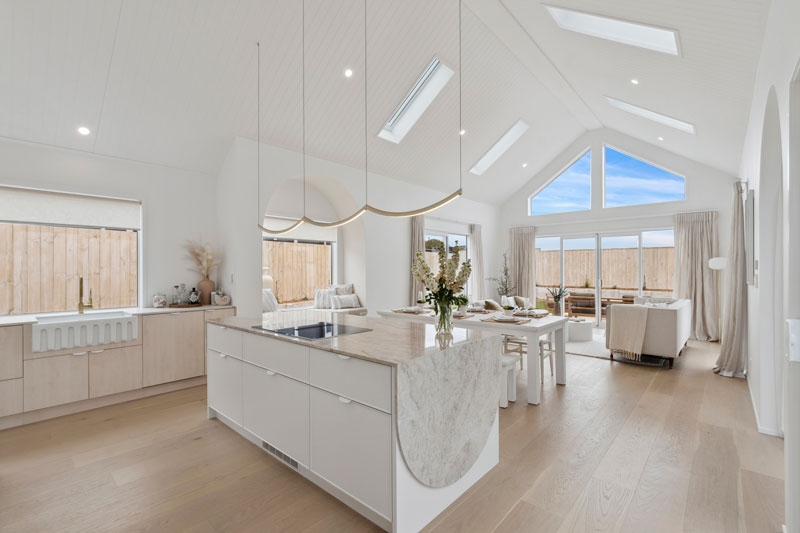 Gorgeous light mediterranean inspired kitchen with brass fittings, arched window seat, arch details on cabinets and benctop in Precision Homes showhome