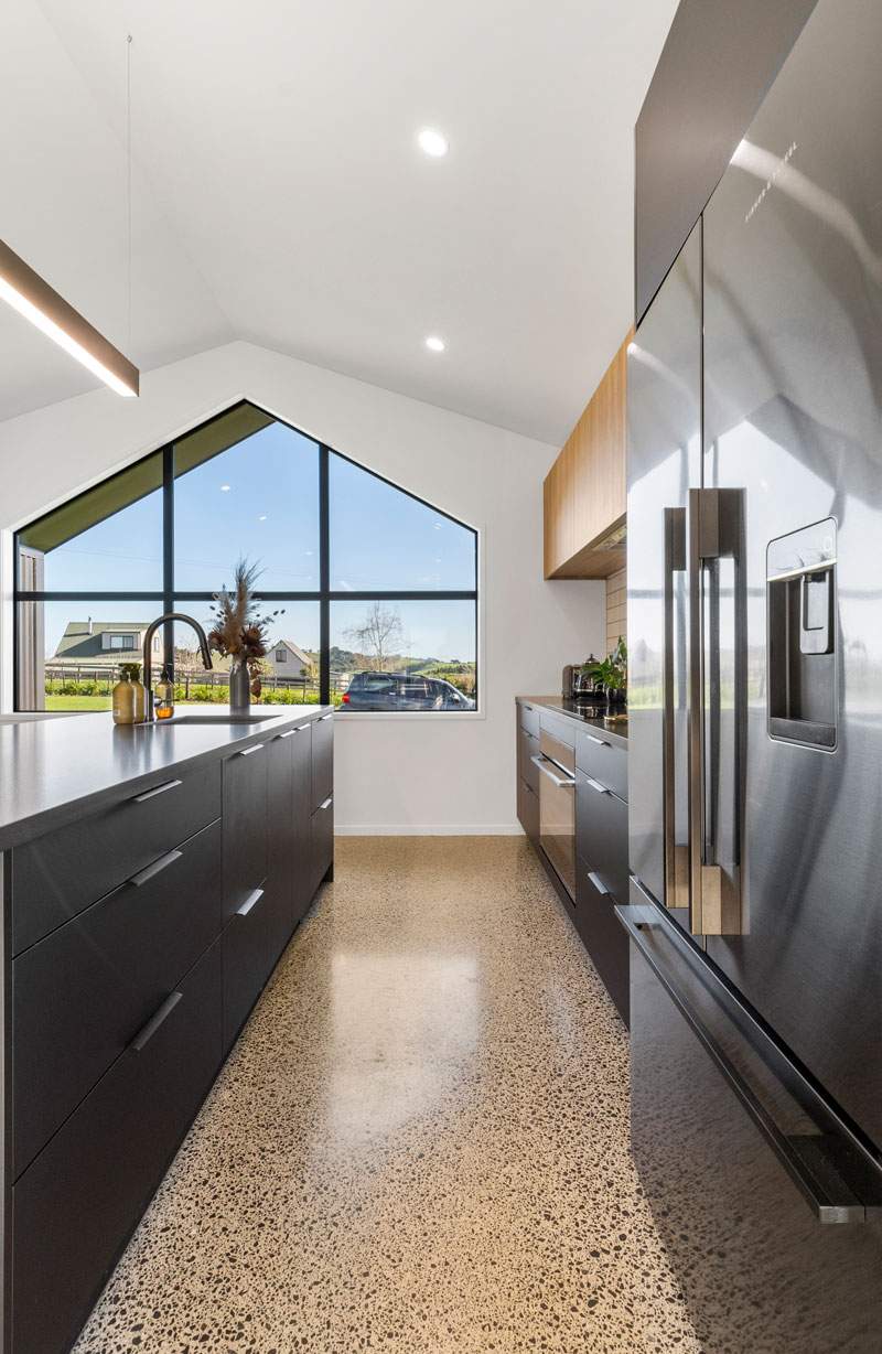 Gorgeous black kitchen with polished concrete floors and large windown in award winning home