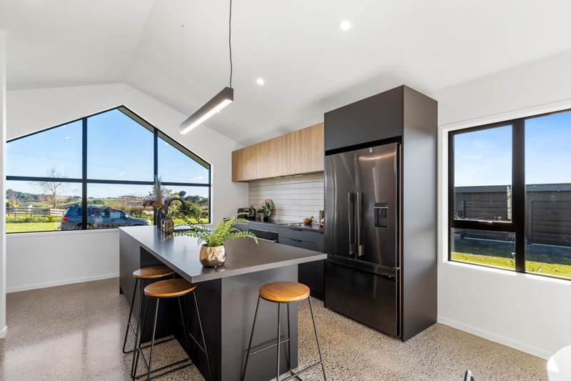 black kitchen with timber accents and polished concrete floors in award winning home Pukekohe